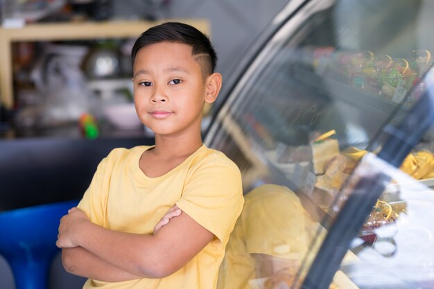 Aziatische jong geitjejongen die bij bakkerijwinkel wachten en bakkerij kiezen die hij houdt van