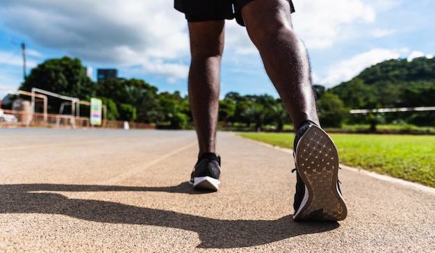 Aziatische jonge atleet sportloper zwarte man draagt voeten actief klaar om te trainen buiten op de loopbandlijnweg voor een stap voorwaarts, gezonde oefeningstraining, close-up achterschoen