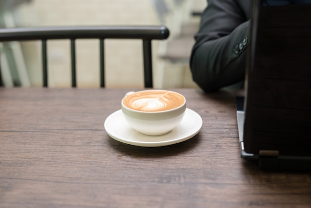 Aziatische jonge bedrijfsmens die met laptop in de koffie van de koffiewinkel werken