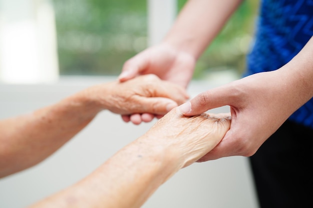 Aziatische jonge jongen die de hand van de oude grootmoedervrouw samen met liefde en zorg houdt