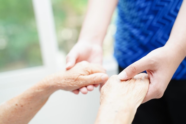 Aziatische jonge jongen die de hand van de oude grootmoedervrouw samen met liefde en zorg houdt