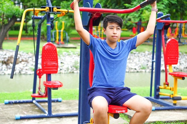 Aziatische jonge man die het slimme horloge draagt, oefent in het park met fitnessapparatuur voor buiten