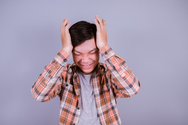 Foto aziatische jonge man draag een gestreepte staande op een grijze achtergrond met de hand op hoofdpijn omdat stress lijdt aan migraine