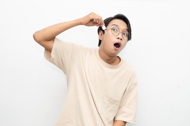 aziatische jonge man in casual beige t-shirt die schoonheidsacne-serum aanbrengt met behulp van een pipet