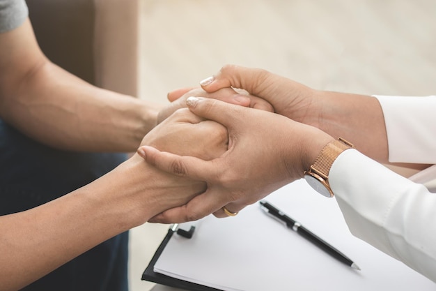 Aziatische jonge man, man lijdt aan mentale behoefte aan therapie met psycholoog terwijl hij op de bank zit, overlegt met psychiater en moedigt patiënt aan door aan te raken, vast te houden om hem ontspannen te laten voelen.