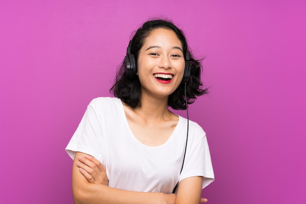 Aziatische jonge meisje het luisteren muziek met mobiel en het zingen over geïsoleerde purpere muur