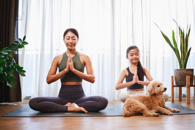Aziatische jonge moeder en haar dochter bereiden zich voor op yoga en meditatie samen thuis