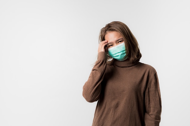 Aziatische jonge vrouw die een hygiënisch beschermend masker over haar gezicht op Witte achtergrond, Coronavirus covid-19 draagt