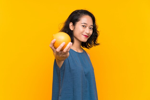 Aziatische jonge vrouw die een sinaasappel houdt