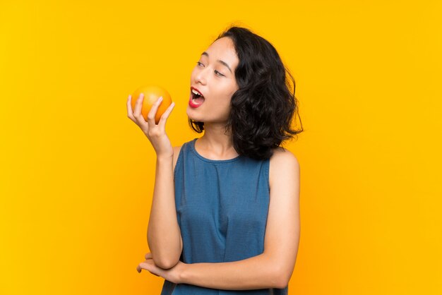 Aziatische jonge vrouw die een sinaasappel houdt