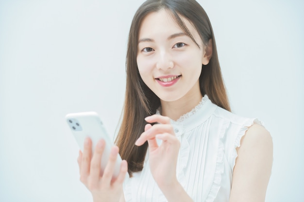 Aziatische jonge vrouw die een smartphone bedient
