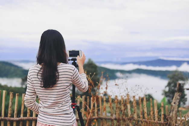 Foto aziatische jonge vrouw die foto met smartphone op berg neemt