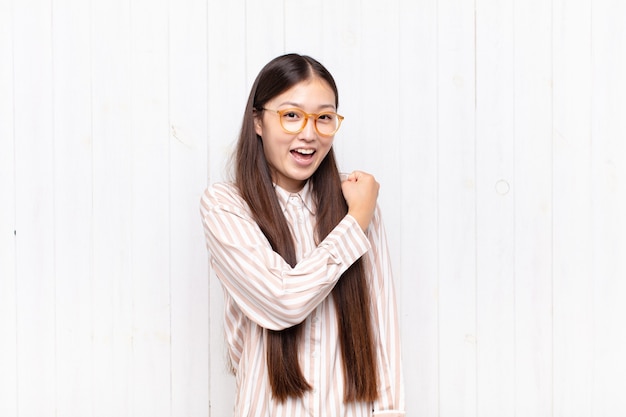 Aziatische jonge vrouw die gelukkig, positief en succesvol geïsoleerd voelt