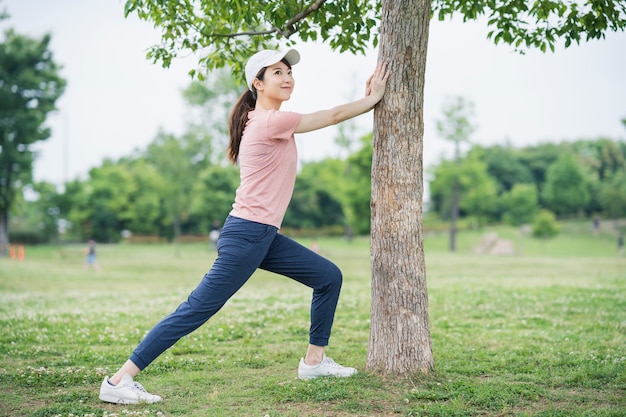 Aziatische jonge vrouw die in het park uitoefent