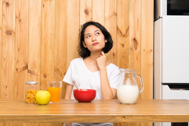 Aziatische jonge vrouw die ontbijtmelk heeft die een idee denkt