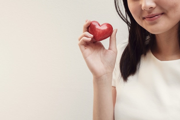 Aziatische jonge vrouw die rood hart houdt