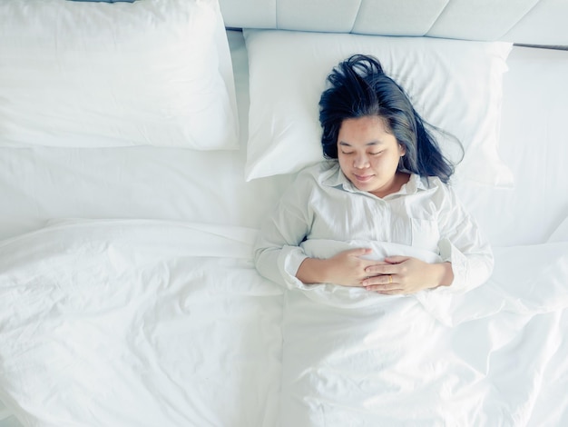 Aziatische jonge vrouw die zich in de ochtend uitstrekt wakker wordt in de slaapkamer op bed persoon