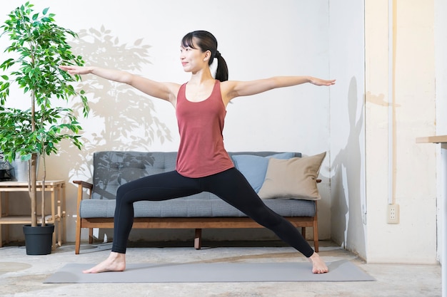 Aziatische jonge vrouw doet yoga in de kamer