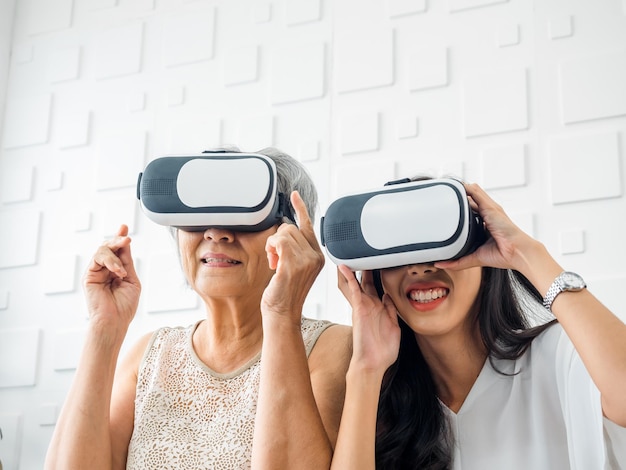 Aziatische jonge vrouw gelukkige dochter en haar moeder oude senior vrouw met VR-bril genieten van 3D-spel online samen in witte kamer Moeder en dochter met realiteit virtuele technologie levensstijl concept