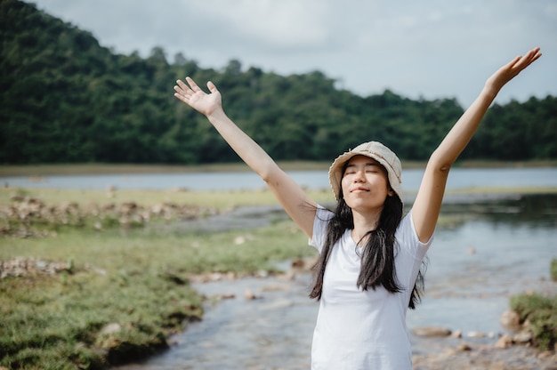 Aziatische jonge vrouw genieten van en ontspannen met de natuur, gebied van waterstroom, waterval buiten