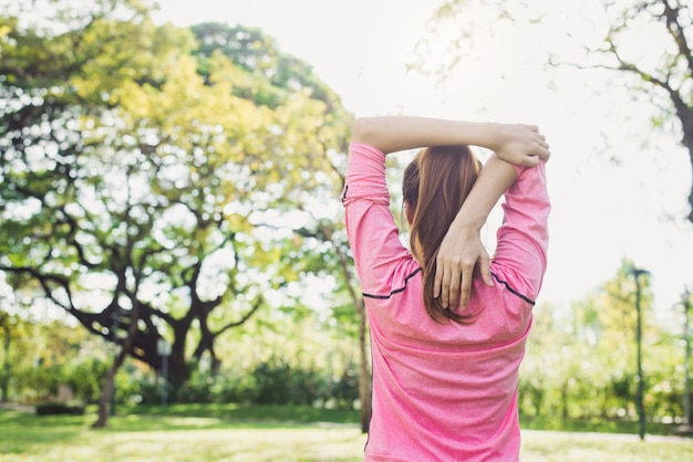 Aziatische jonge vrouw opwarmen het lichaam die zich uitstrekt voor ochtendoefening en yoga in het park