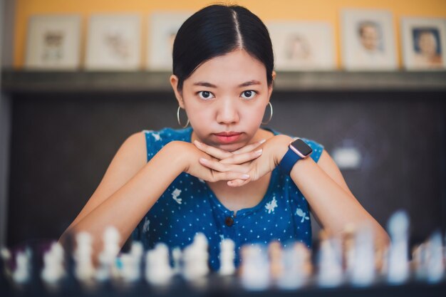 Aziatische jonge vrouw thuis schaken