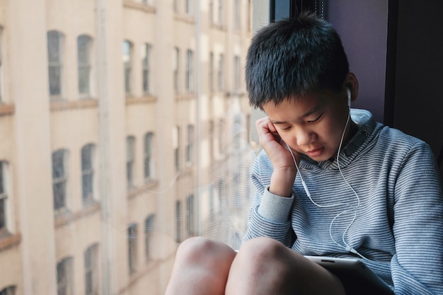 Aziatische jongen die digitale tablet thuis gebruiken