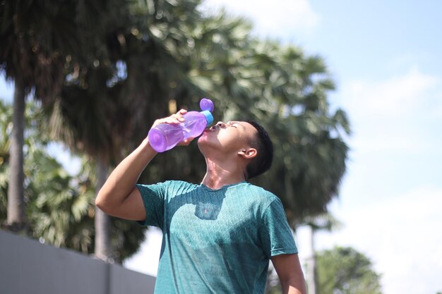 Aziatische jongen die gebotteld water drinkt na het hardlopen