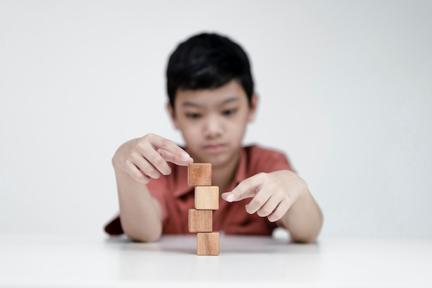 Foto aziatische jongen die houten kubussen, educatieve concepten kiest en leert in een nieuw normaal.