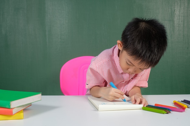 Aziatische Jongen die in schoolbordruimte schrijft