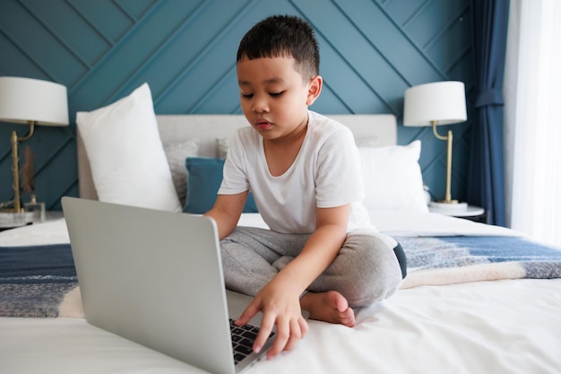 Aziatische jongen die laptop gebruikt om online te studeren met een videogesprekleraar in de slaapkamer voor leren op afstand