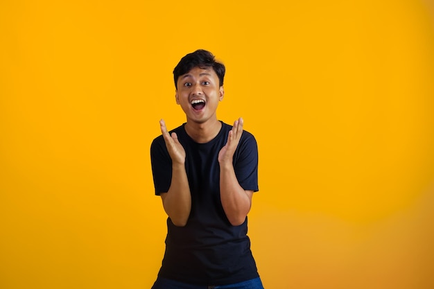 Aziatische jongen die verrassing uitdrukt wanneer hij een geschenk vooraanzicht op gele achtergrond krijgt