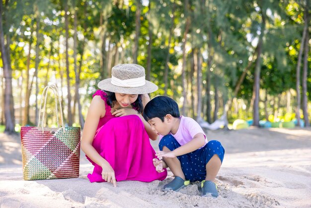 Aziatische jongen en moeder vrouw ontspannen op tropisch strand ze genieten van vrijheid en frisse lucht met stijlvolle hoed en kleding gelukkig lachende toerist in tropen in reisvakantie