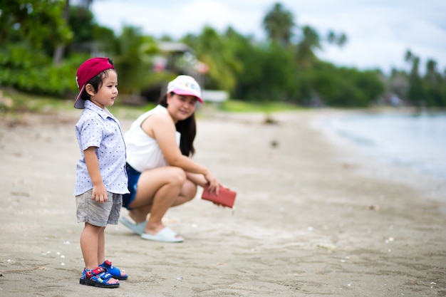 Aziatische jongen en moeder wandelen op het tropische strand, Gelukkig jongetje wandelen in de buurt van de zee