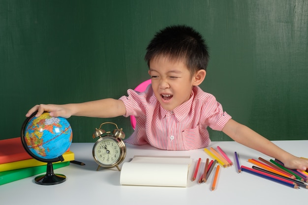 Aziatische jongen geniet van leren in een schoolbord kamer