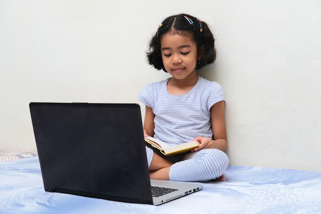 Aziatische jongen leest een boek tijdens het studeren in haar bed