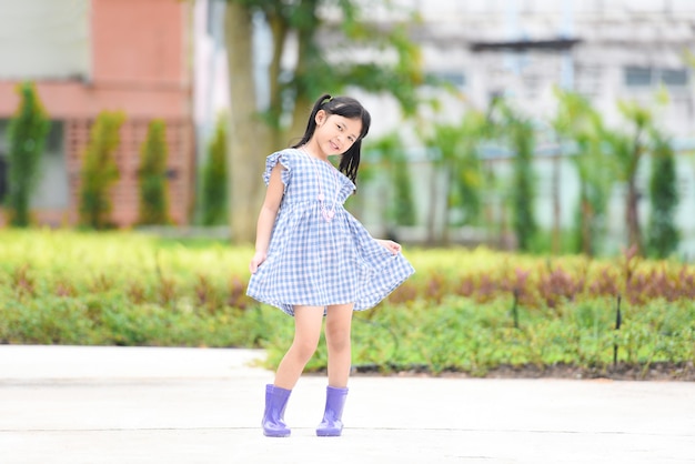 Aziatische jongen meisje gelukkig in de park tuin boom achtergrond, mooi kind plezier buiten spelen met gelukkige glimlach kinderen buiten spelen meisje portret dragen kleurrijke laarzen