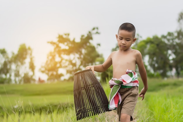 Aziatische jongen om tijdens de vakantie op groen landbouwbedrijfgebied te vissen in zomer