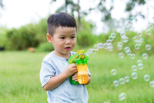 Aziatische jongen speelt met bubbelspuiter.