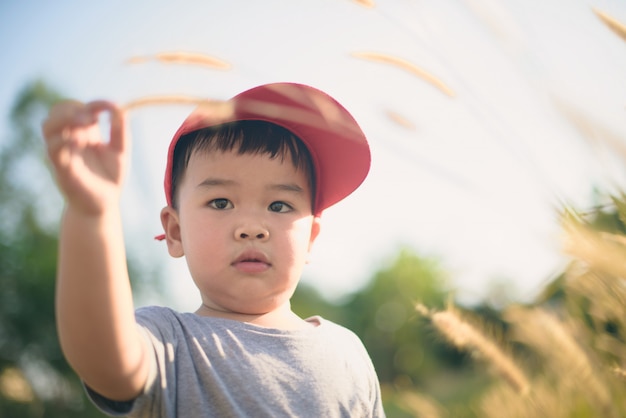 Aziatische jongen spelen buiten met droge grassen