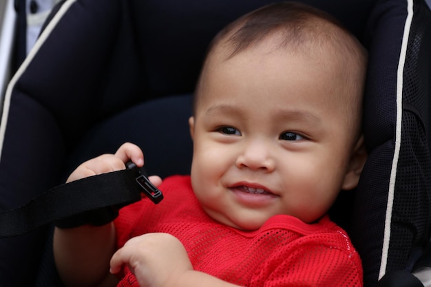 Aziatische jongen zit gelukkig op een kinderwagen