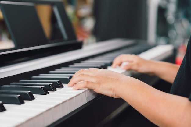 Aziatische jongens die de piano spelen.