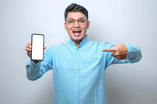 Aziatische kerel Glimlach op zoek naar camera Weergeven van smartphone leeg scherm Aanbeveling van toepassing