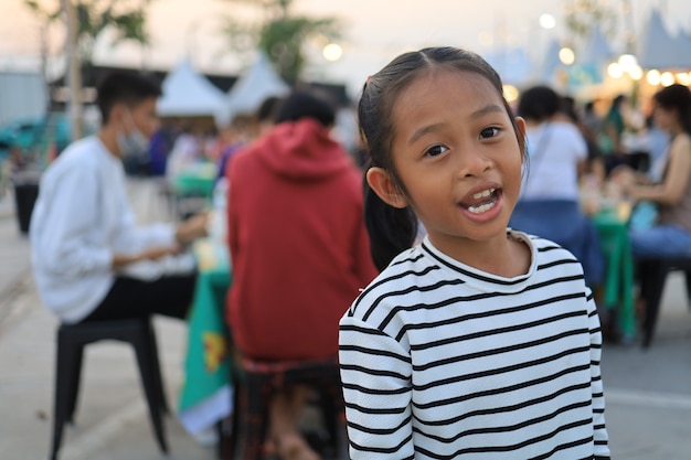 Aziatische kinderen die overdag in het voedselfestival zitten en eten