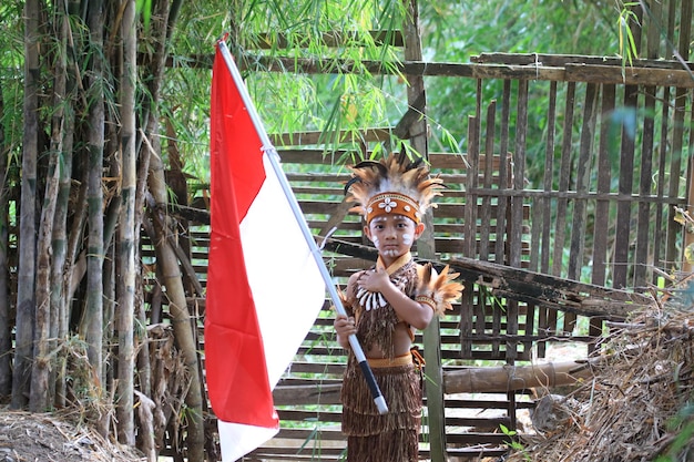 AZIATISCHE KINDEREN DIE TRADITIONELE KLEDING VAN PAPOEA DRAGEN EN INDONESISCHE VLAG DRAGEN