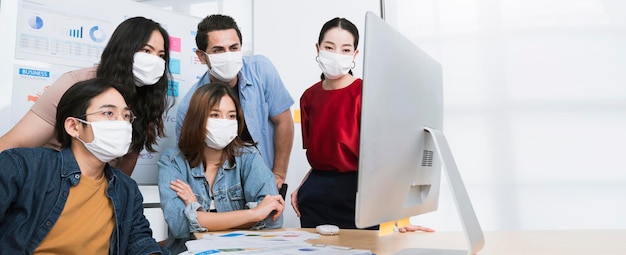 Aziatische kleine bedrijven opstarten multiraciale brainstormvergadering met laptop en grafiekpapier iedereen masker voor covid19 bescherming corona griep voorkomen gezonde ideeën concept kantoorachtergrond