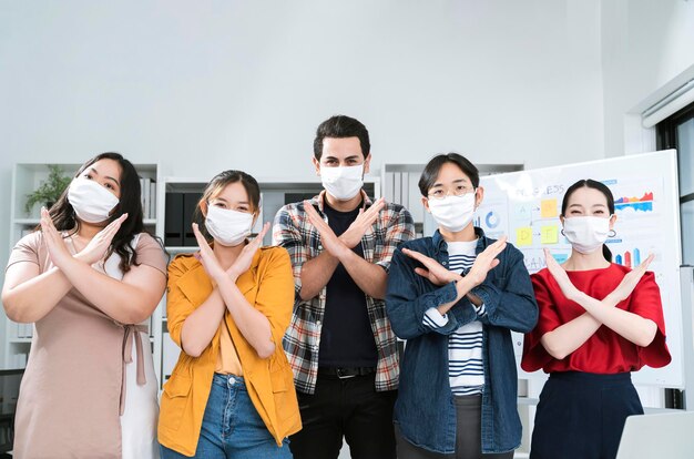 Aziatische kleine bedrijven opstarten multiraciale vechtactie houding met laptop en kaartpapier iedereen masker voor covid19 bescherming corona griep voorkomen gezonde ideeën concept kantoor achtergrond