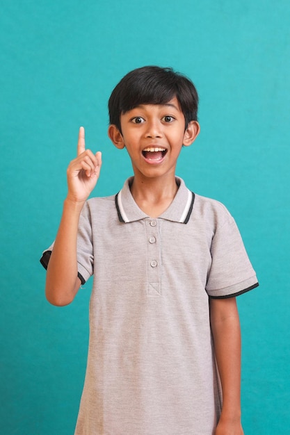 Aziatische kleine jongen die gebaar van een idee doet met de vinger omhoog geïsoleerd over groene achtergrond