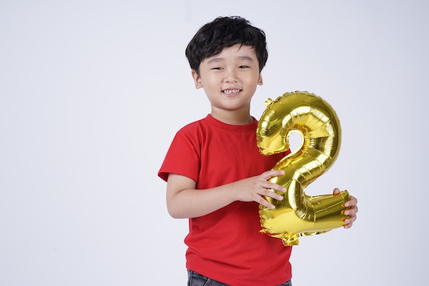 Aziatische kleine jongen jongen gelukkige glimlach met folie nummer ballon, geïsoleerd op een witte achtergrond