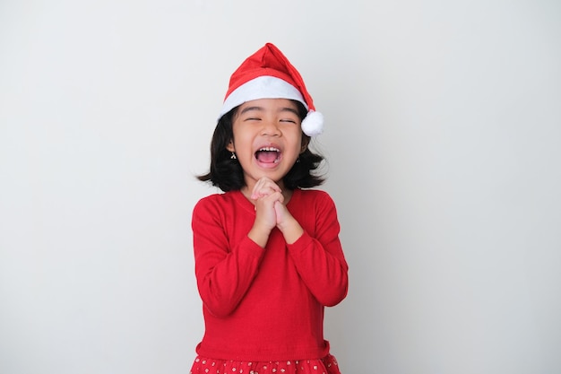 Aziatische kleine jongen met een kerstmuts die een blije gezichtsuitdrukking laat zien tijdens het bidden